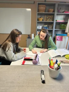 Lektorka v zeleném saku individuálně vysvětluje látku studentce.