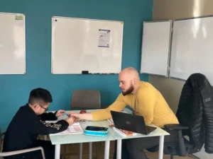 Lektor ve žlutém tričku prochází se studentem zadání přijímacích zkoušek.